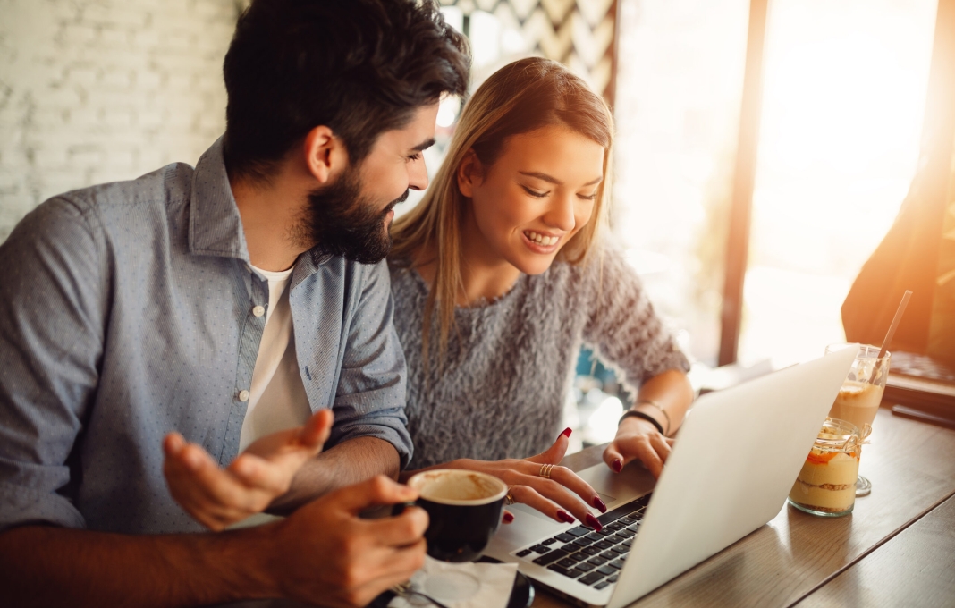 Couple surfing on a laptop at cafe. Couple shopping online or video chatting.